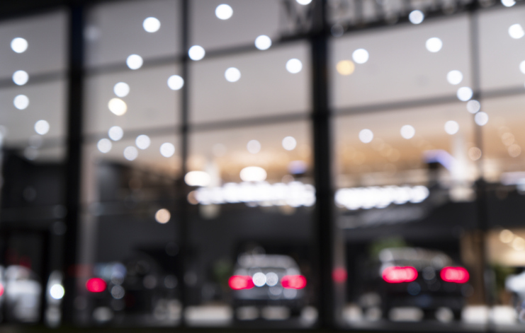 Blurred background with car dealership exterior. Abstract blurred photo of modern building motor showroom. Blur car show room office bokeh lights. Automobile retail shop