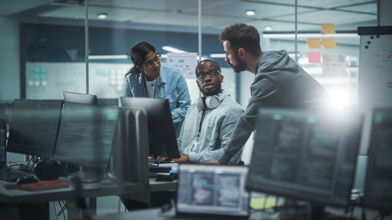 Diverse Group of Professionals Meeting in Modern Office: Brainstorming IT Programmers Use Computer Together, Talk Strategy, Discuss Planning. Software Engineers Develop Inspirational App Program